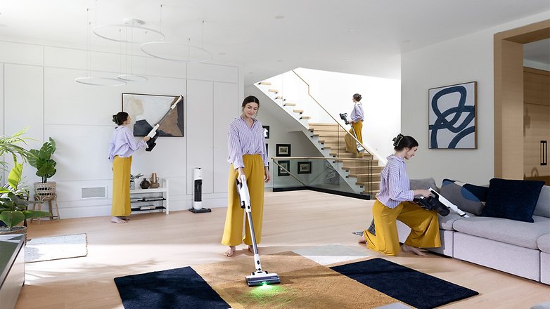 Eine Frau in einem gestreiften Hemd und gelben Hosen saugt ein modernes Wohnzimmer mit dem Tineco Pure One Station 5.
